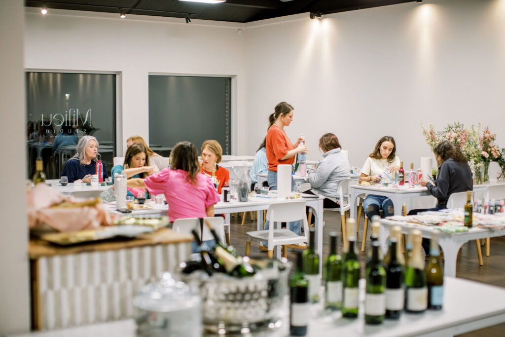 Guests decoupaging wine bottles during Valentine’s floral workshop in Northwest Arkansas