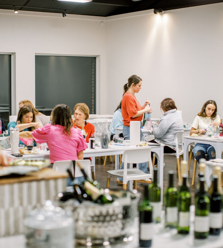 Guests decoupaging wine bottles during Valentine’s floral workshop in Northwest Arkansas